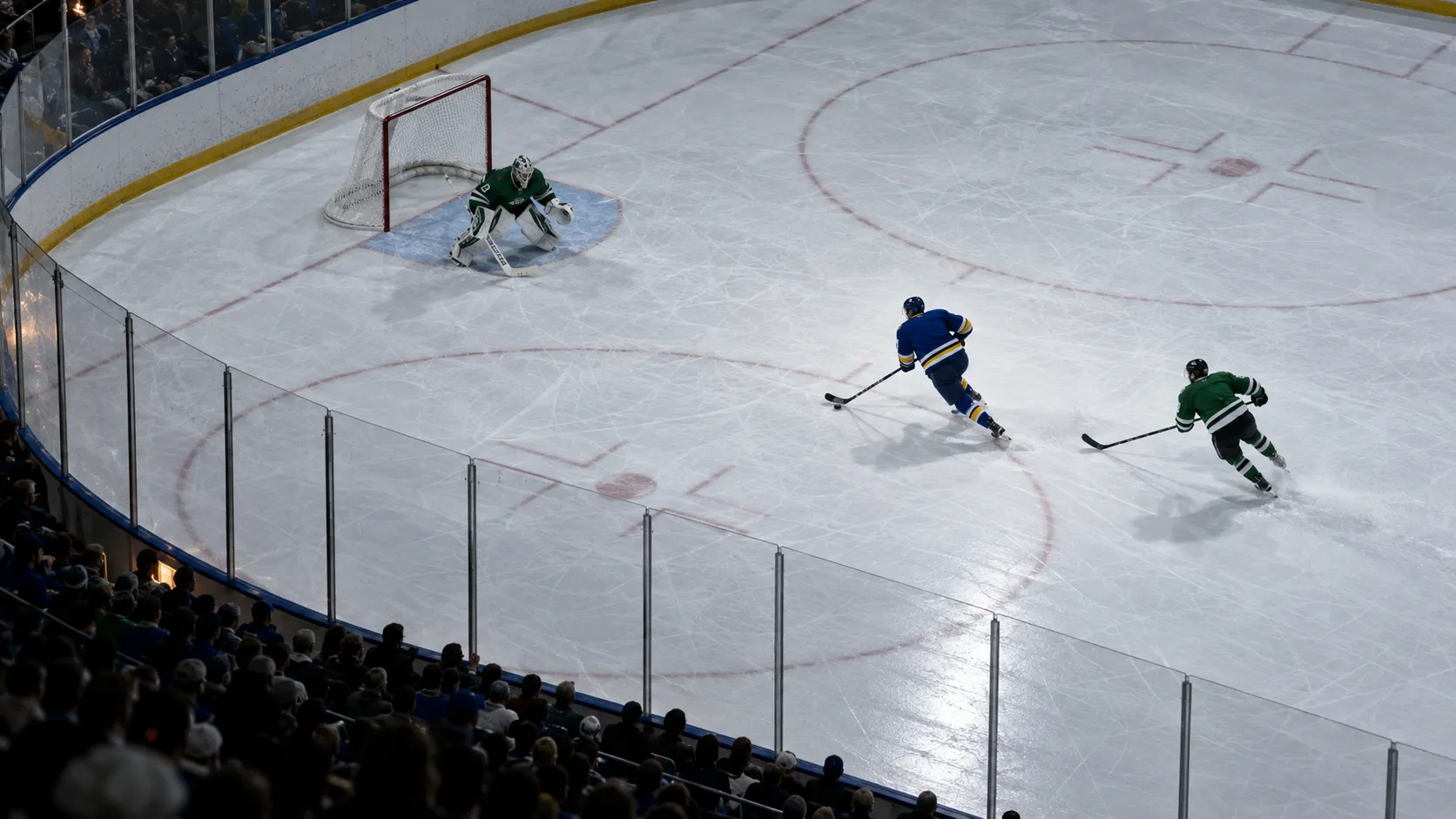 Overhead view of a blue uniformed hockey player breaking towards goal as a green uniformed defender gives chase