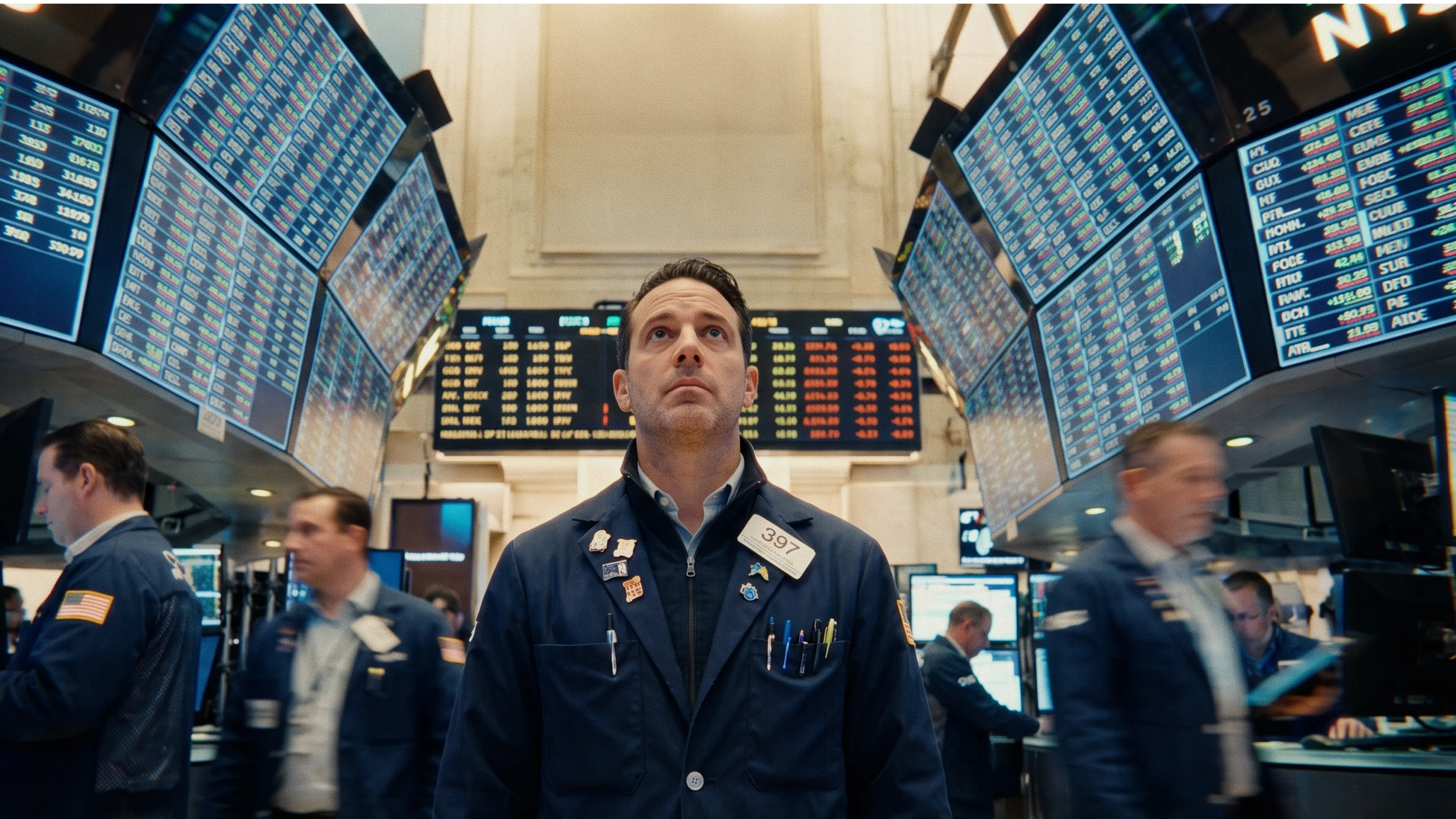 a man standing in room similar to stock trading surrounded by monitors
