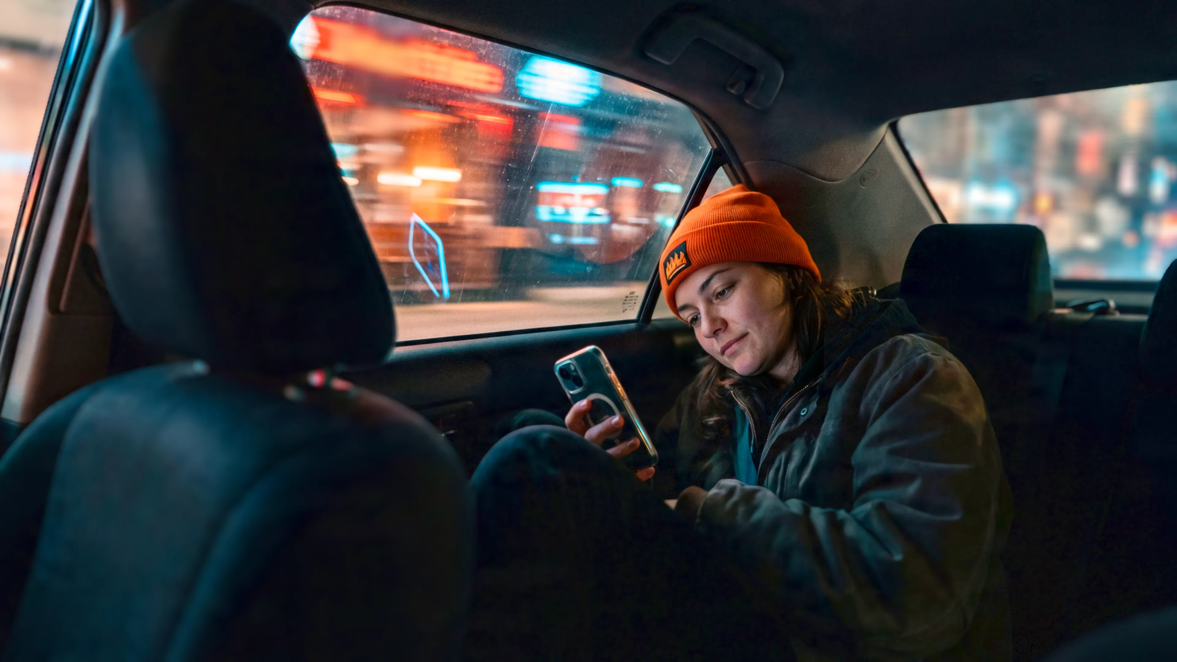 a white woman sitting in a cab looking at her phone